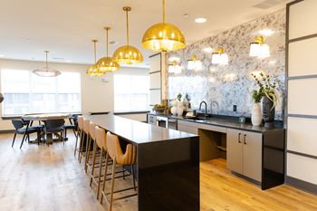 A modern kitchen with a long black island and wooden chairs.